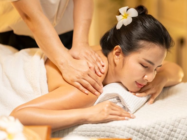 Woman receiving shoulder massage at iCure Massage Woman enjoying a relaxing massage with a flower in her hair.