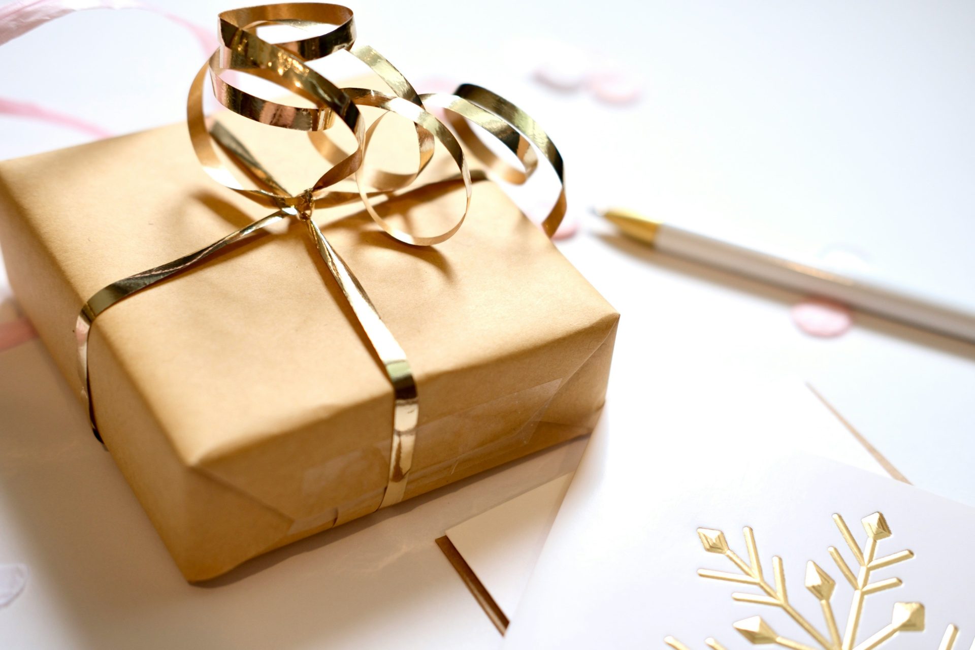 A gift wrapped in brown paper with a gold ribbon